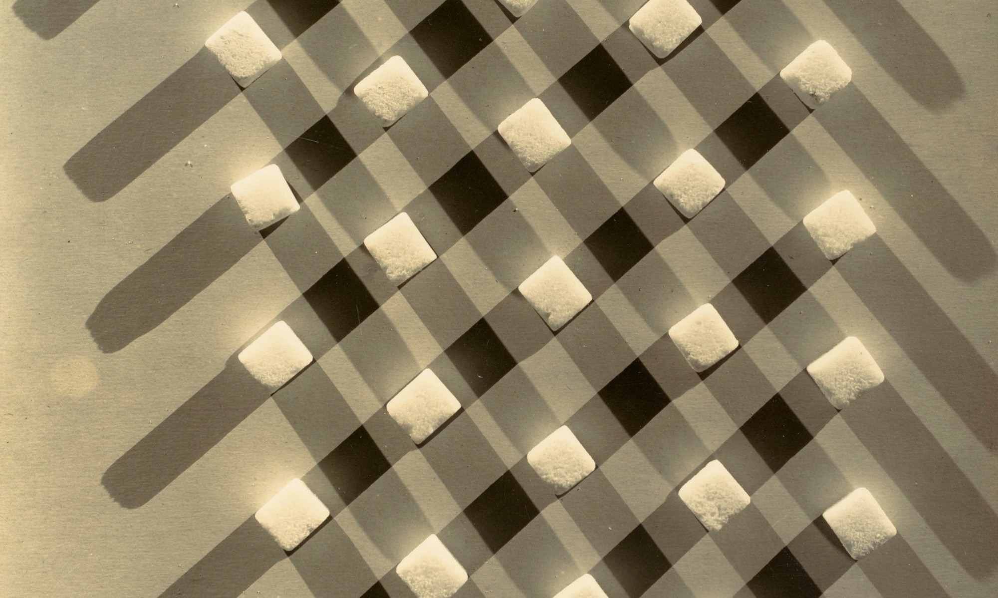 Black-and-white photograph of a grid of sugar cubes with raking shadows
