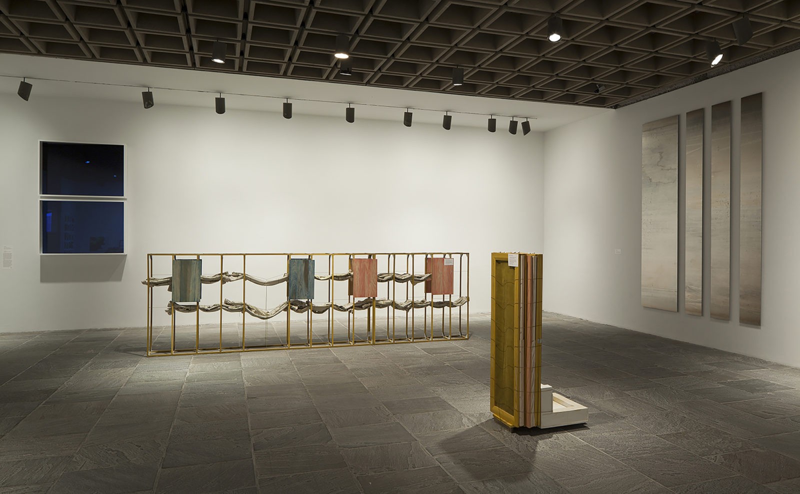 A view of artworks in a gallery, including two sculptures on the floor and six image-free photographs on the walls.